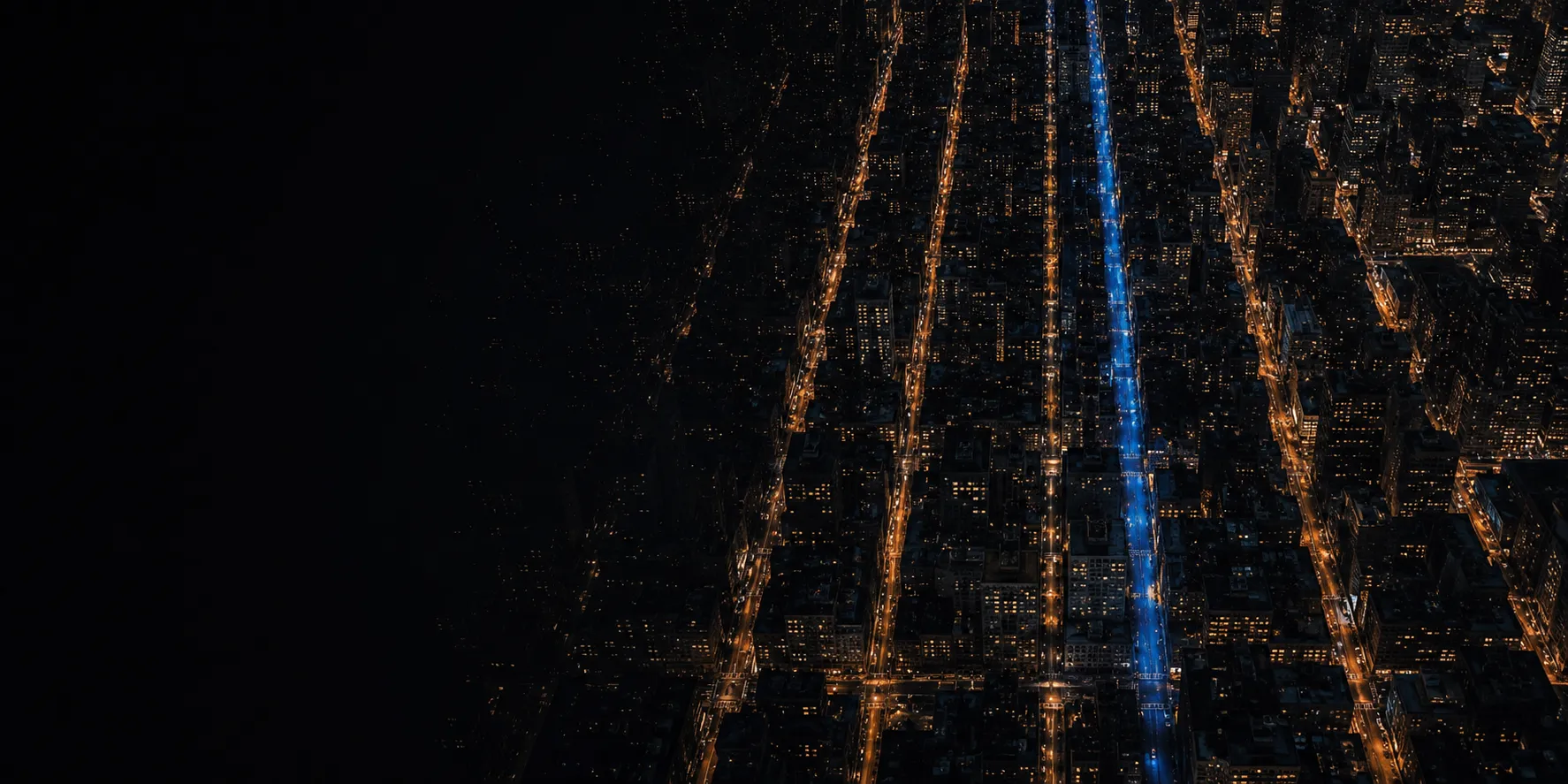 Aerial night view of a dense city grid, streets running in strict parallel rows.